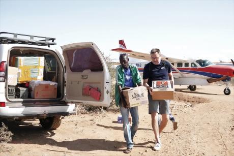 MAF Denmark CEO Peter gives a hand to Pastor Francis as they load goods to the car.