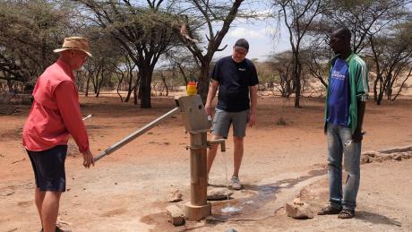 Eddy on the left demonstrating how to draw water from the well to MAF Denmark CEO Peter (middle) and Francis.